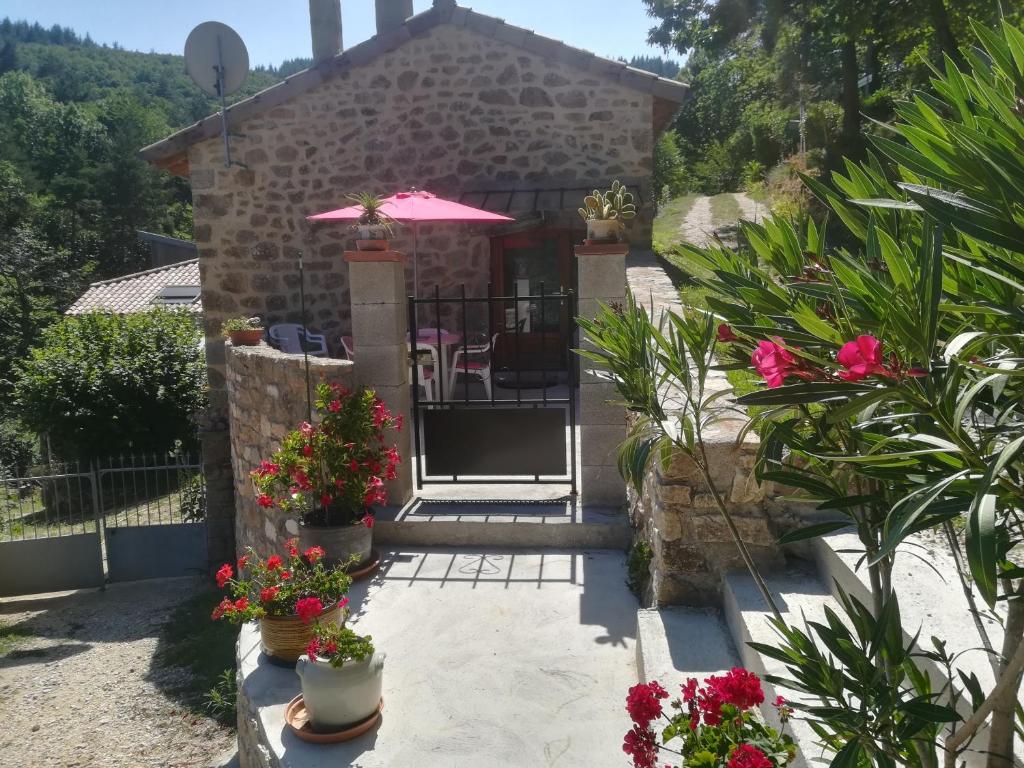 a house with a patio with an umbrella and flowers at LOFT LA ROSE DESIREE Gite 3 étoiles in Chalencon