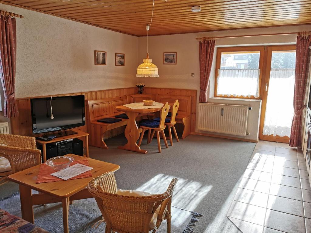 a living room with a table and a television at Ferienhaus-Haidweg-Wohnung-3 in Haidmühle