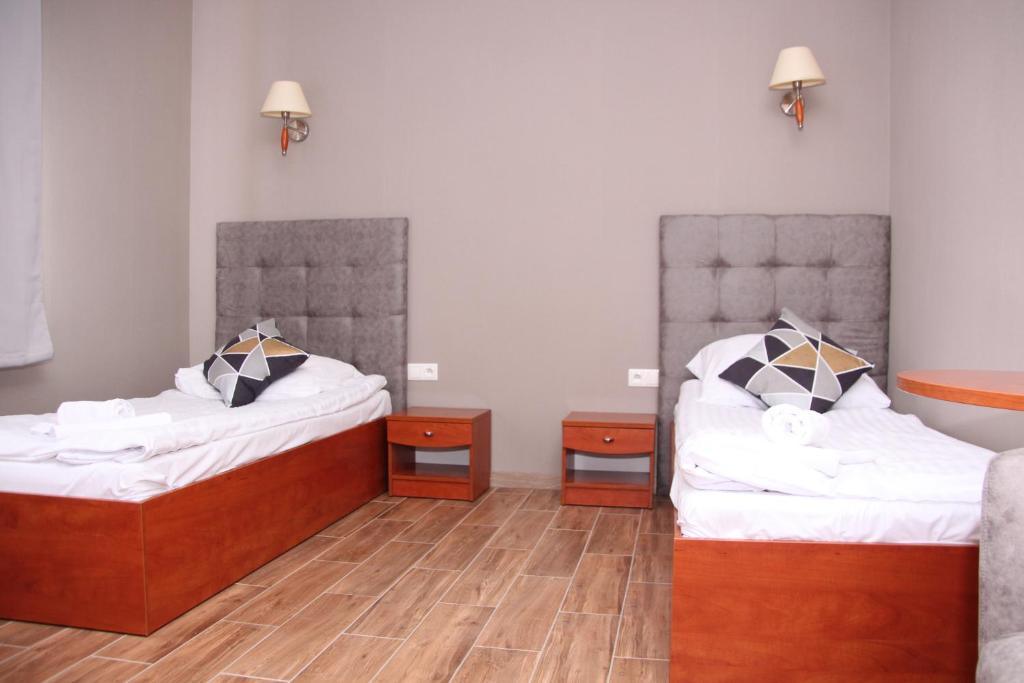 two beds in a room with wooden floors at Hotel Przylesie in Sierosław