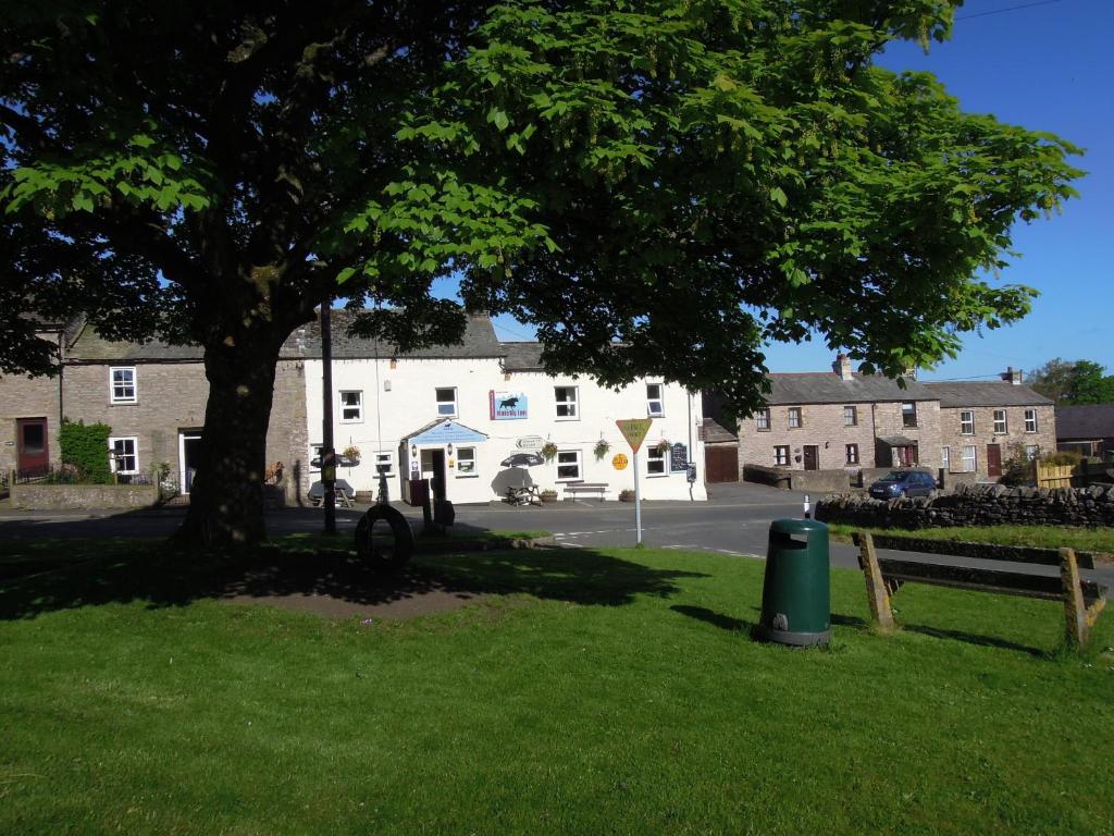 a tree in the grass in front of a building at The Black Bull at Nateby in Kirkby Stephen