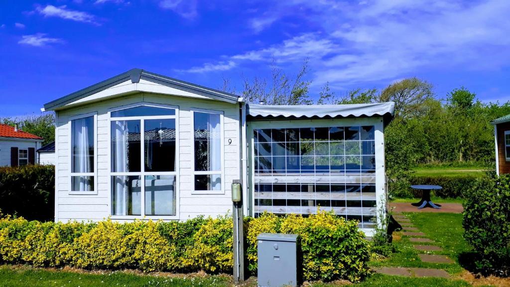 a small white house with a lot of windows at CS 9 - Vakantiepark Callassande in Callantsoog