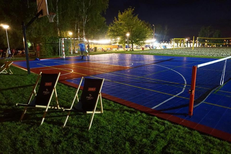 - un terrain de basket la nuit avec 2 chaises dans l'établissement Firlej Plaża, à Firlej