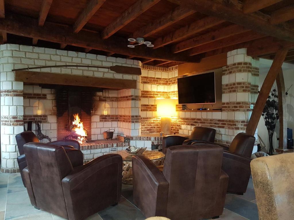 a room with a fireplace with chairs and a television at Le Domaine de Wail - Legends Resort in Wail