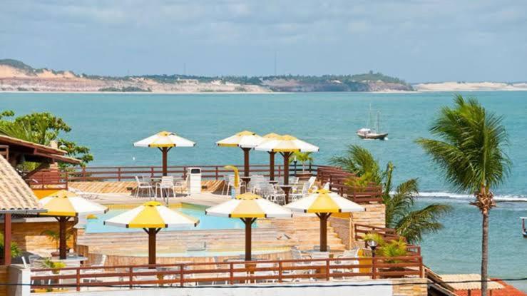 a group of umbrellas on a beach near the water at Casa na Beira da Praia da Pipa Beach House Luxury in Pipa