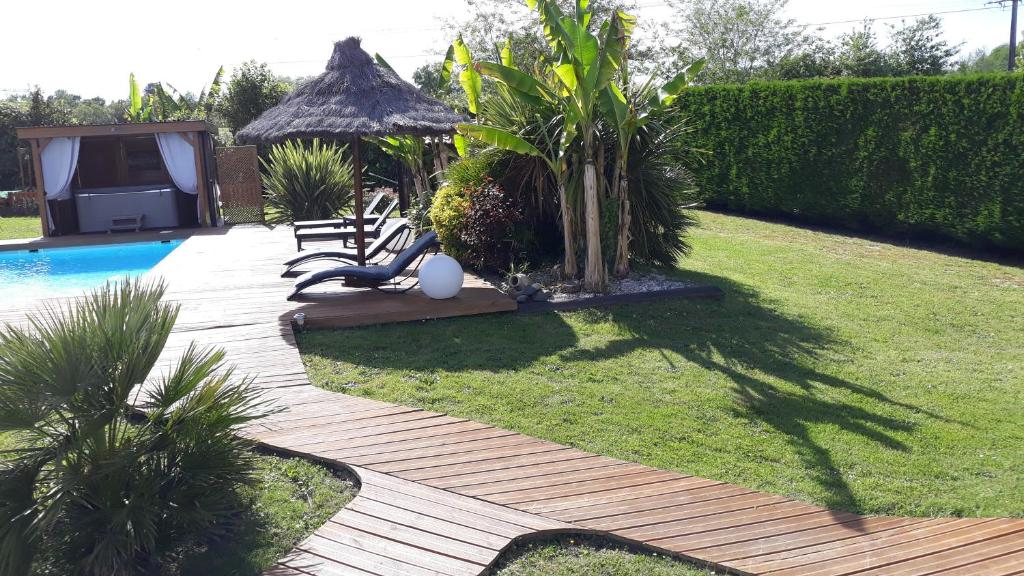 un jardin avec une piscine, une table et un arbre dans l'établissement Chambres d'Hôtes du Hourne, à Saint-Pandelon