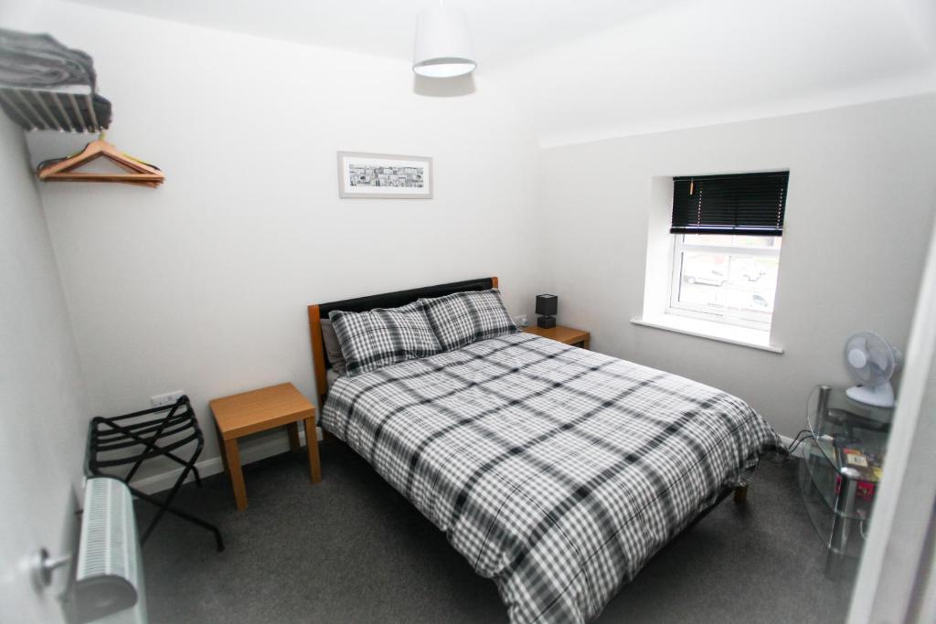 ein Schlafzimmer mit einem Bett mit einer karierten Decke und einem Fenster in der Unterkunft 4a Smart Apartments in Newark upon Trent