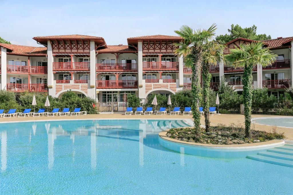 um resort com uma grande piscina e palmeiras em Résidence Pierre & Vacances Le Domaine de Gascogne em Biscarrosse