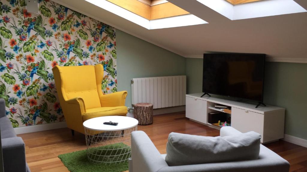 a living room with a tv and a yellow chair at Antigua Ventanas del Cielo, BAJA in Ávila