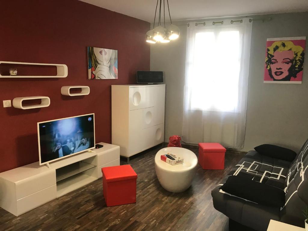 a living room with a television and red walls at APPARTEMENT STYLE POP ART avec GARAGE CENTRE HISTORIQUE BEZIERS in Béziers