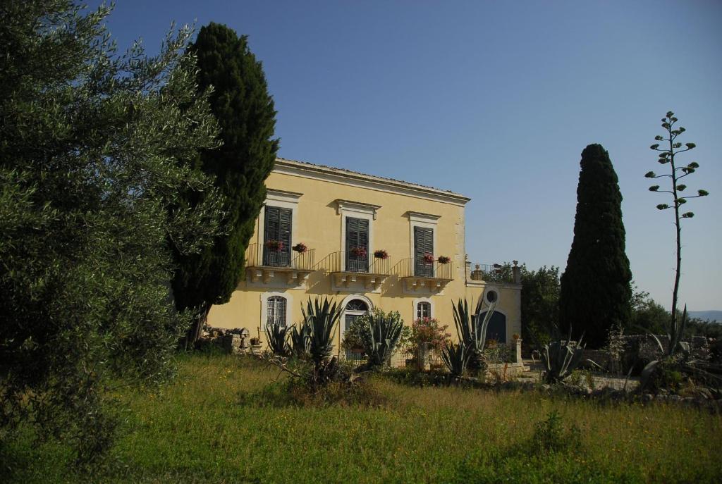 een wit huis met twee ramen en planten in een veld bij Agriturismo Baglio Calanchi in Modica