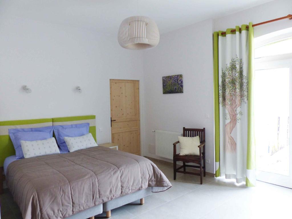 a bedroom with a bed and a chair at L ' AMIRADOU in Félines-sur-Rimandoule