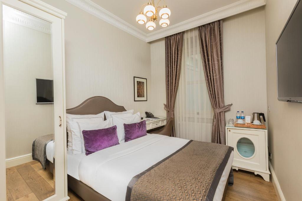 イスタンブールにあるメロッディ ガラタ マンションの大きなベッドと紫色の枕が備わるホテルルームです。