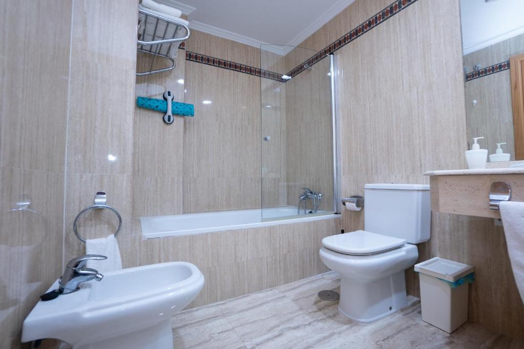 a bathroom with a toilet and a sink and a tub at Apartamentos Jimmy in Nerja