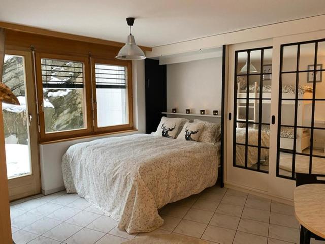 1 dormitorio con cama, mesa y ventanas en Studio Brunnmatt, en Zermatt