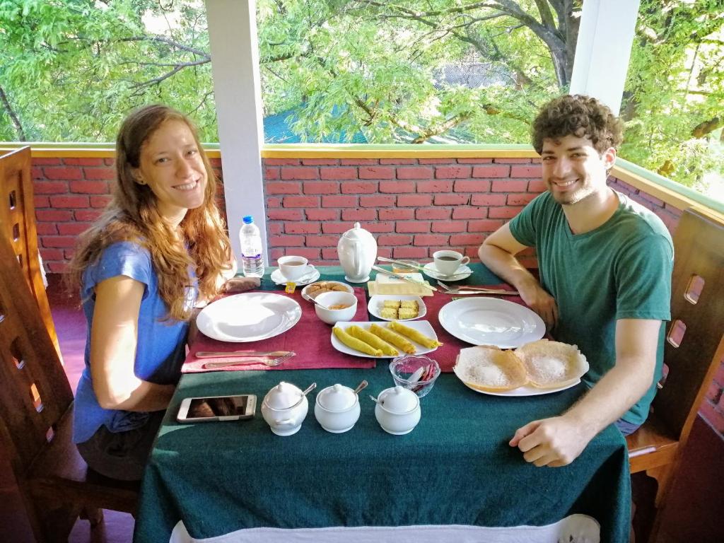 un hombre y una mujer sentados en una mesa con comida en Sigiriya Ranasinghe Nature Villa, en Sigiriya