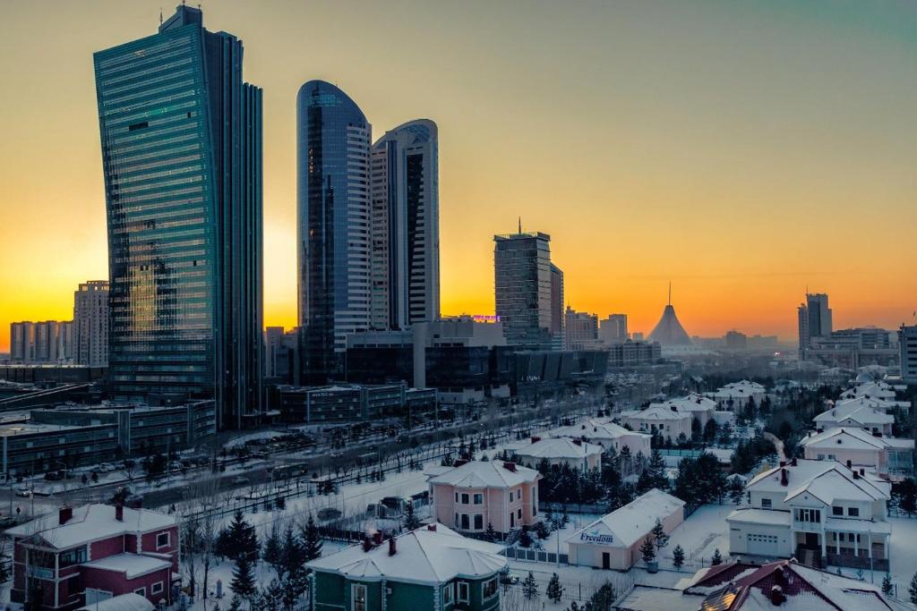 uno skyline della città con edifici alti e tetti ricoperti di neve di ЖК Дипломат a Astana