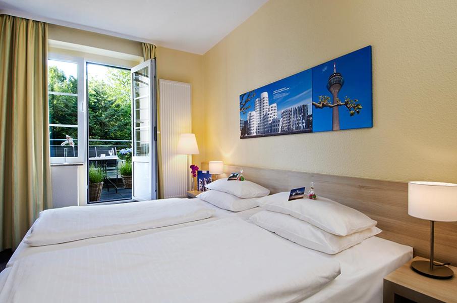 a large white bed in a room with a window at Hotel am Hofgarten in Düsseldorf