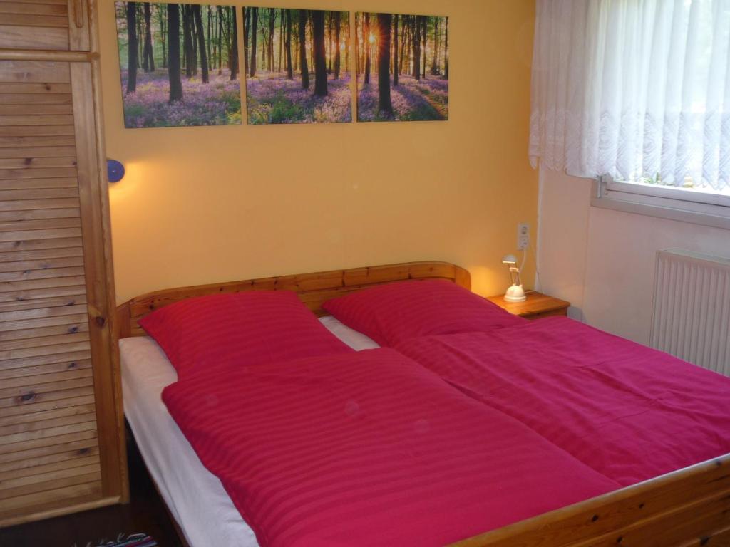 uma cama com lençóis vermelhos num quarto em Ferienhaus Bad Hundertpfund Typ A em Großbreitenbach