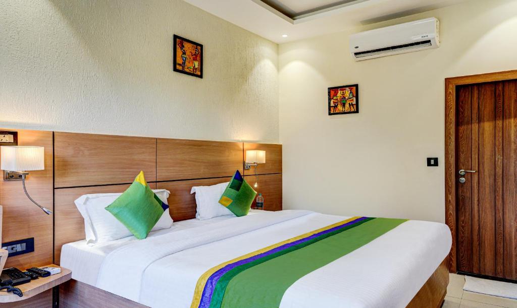 sypialnia z dużym białym łóżkiem z zielonymi poduszkami w obiekcie Hotel Sun Grand w mieście Dehradun
