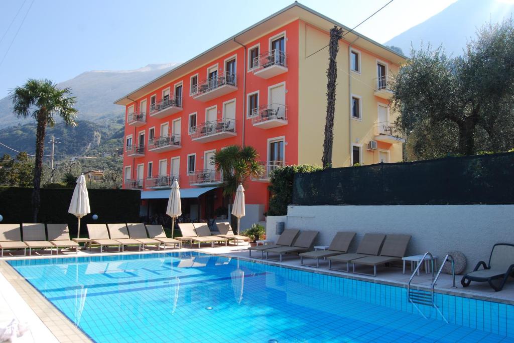 a swimming pool with chairs and a building at Hotel Diana in Malcesine