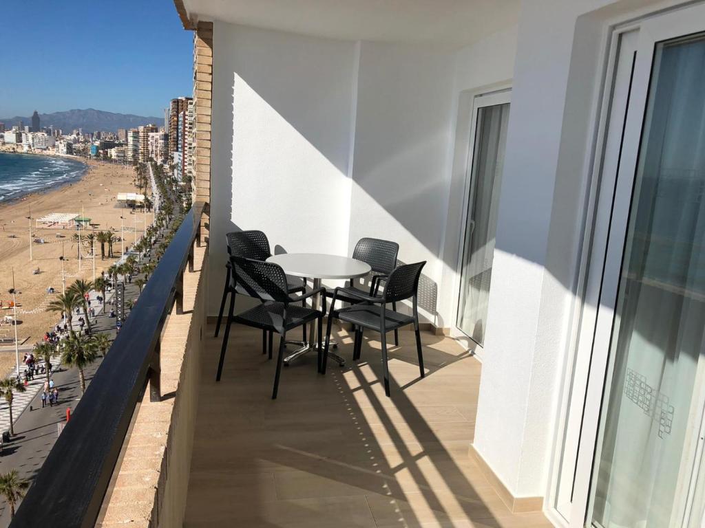 a balcony with a table and chairs and the beach at Les Dunes Comodoro in Benidorm