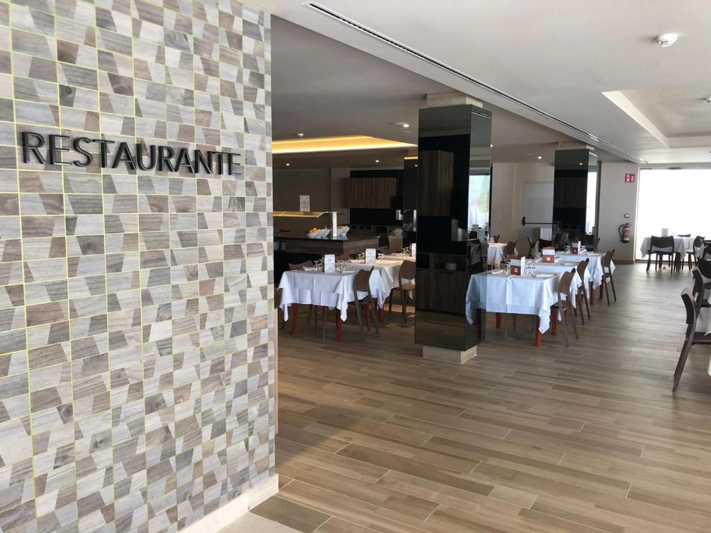 a restaurant with tables and chairs and a restaurant sign on a wall at Les Dunes Comodoro in Benidorm