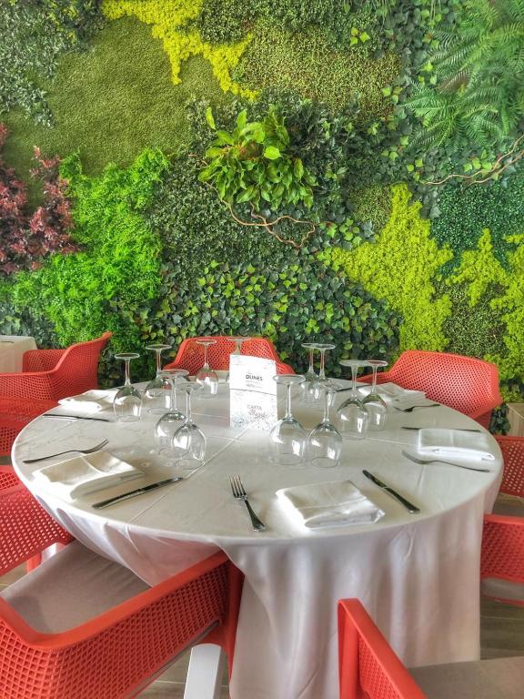 a white table with red chairs and a wall of grapes at Les Dunes Comodoro in Benidorm