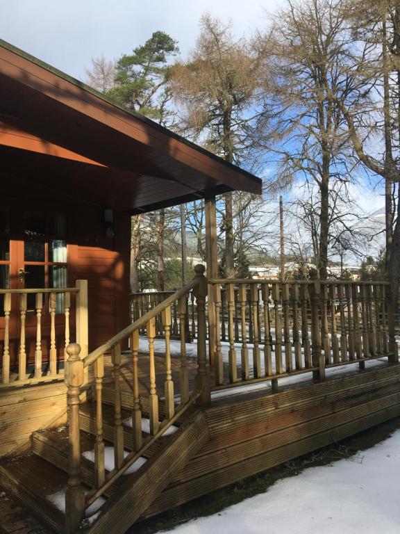 a wooden porch of a cabin with a wooden railing at Chalet in Tyndrum