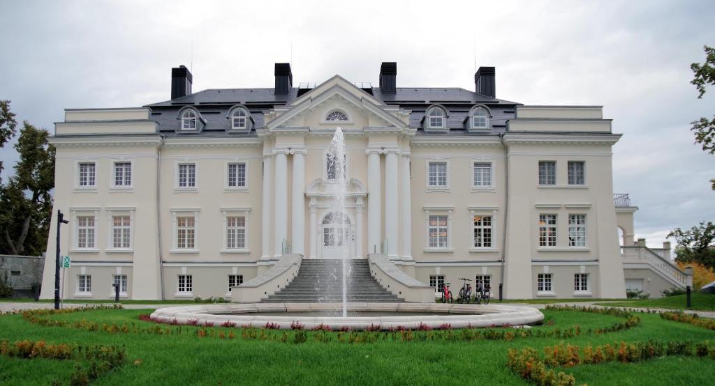 a white house with a fountain in front of it at Pałac Komierowo in Sępólno Krajeńskie