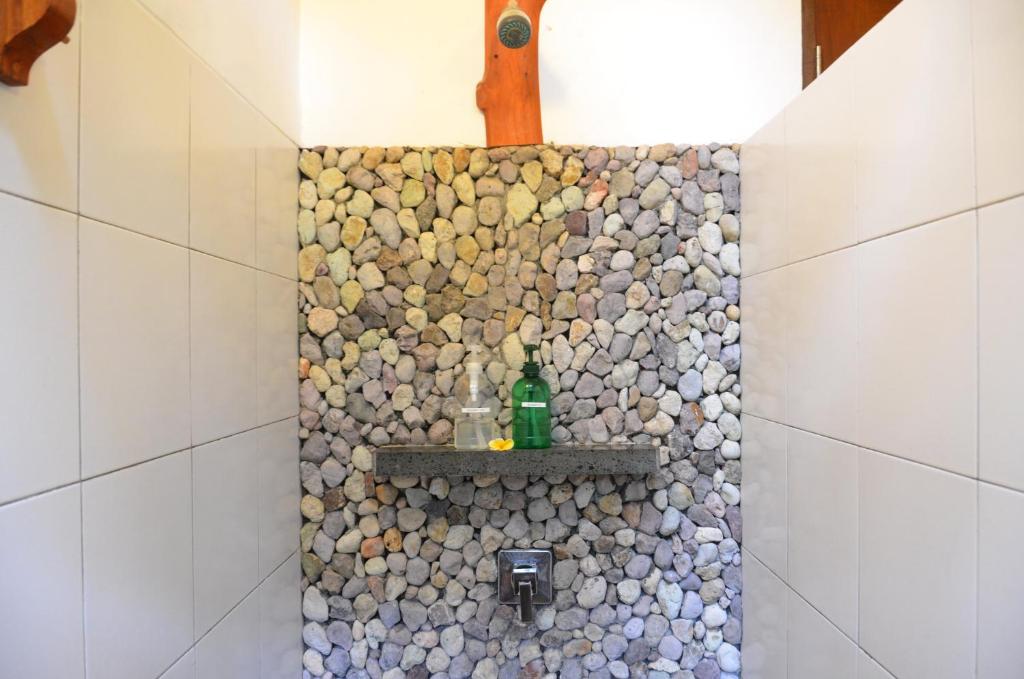 a bathroom with a shower with a stone wall at Cocotinos Sekotong Lombok in Sekotong