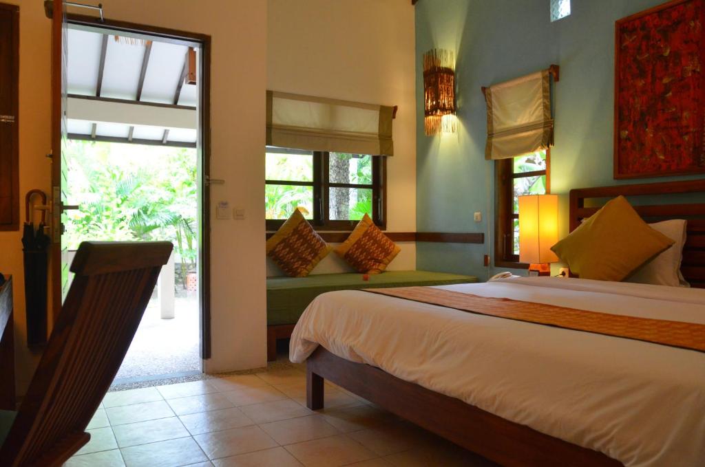 a bedroom with a bed and a couch and windows at Cocotinos Sekotong Lombok in Sekotong