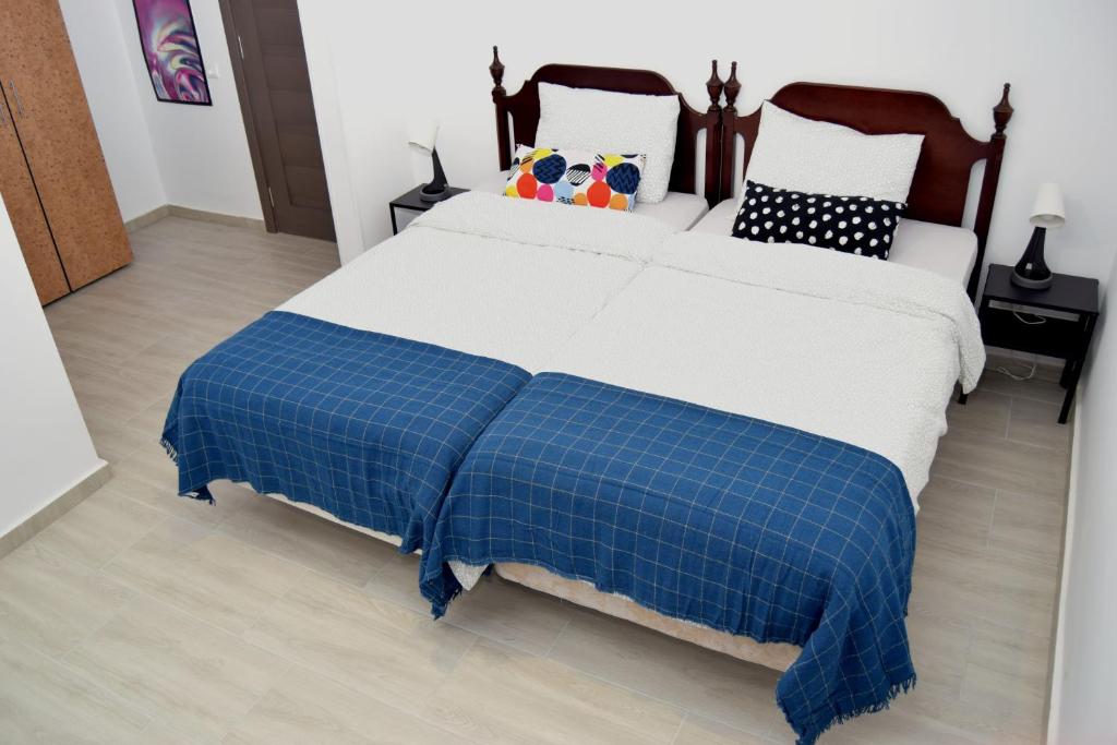 a bed with a blue and white blanket on it at Hotel Road Rooms in Voluntari