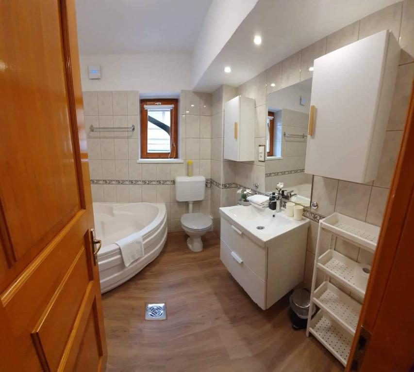 een badkamer met een bad, een toilet en een wastafel bij Pannonia Apartman in Esztergom