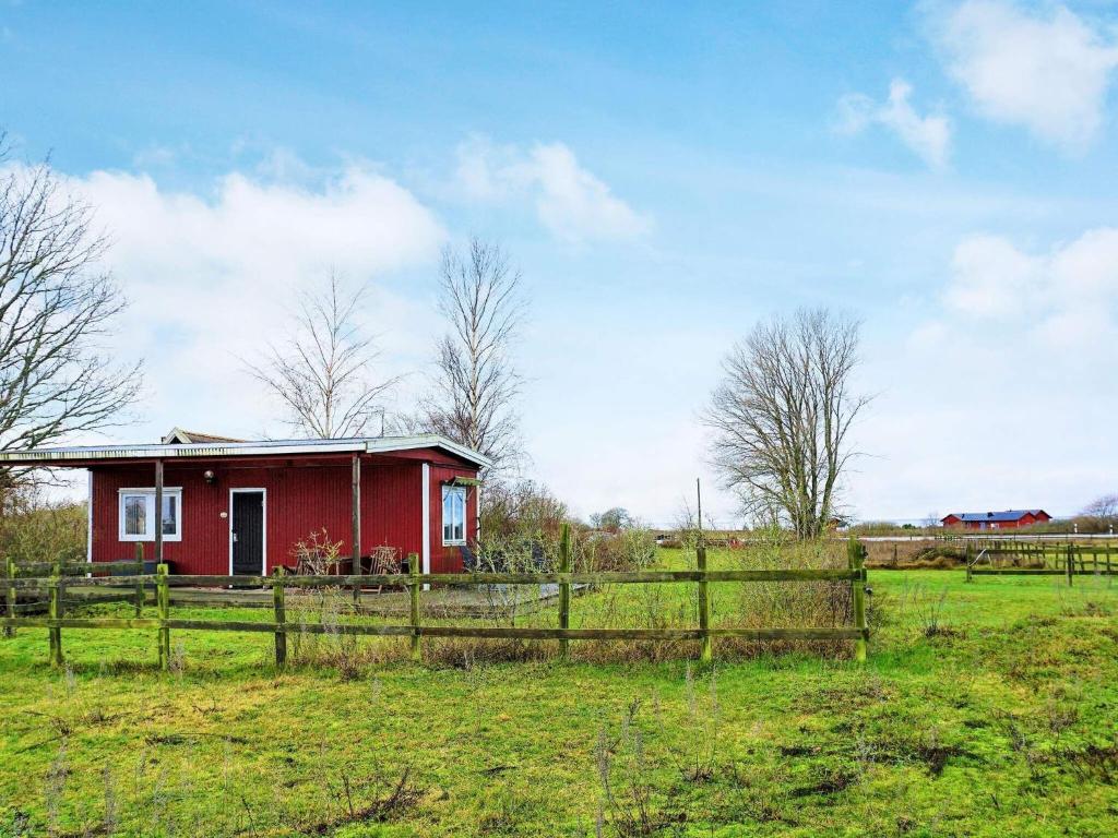une maison rouge dans un champ à côté d'une clôture dans l'établissement 4 person holiday home in GOTLANDS TOFTA, à Västergarn