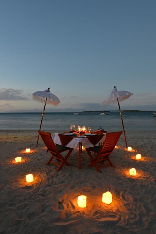 a table and chairs on the beach with candles at Cocotinos Sekotong Lombok in Sekotong