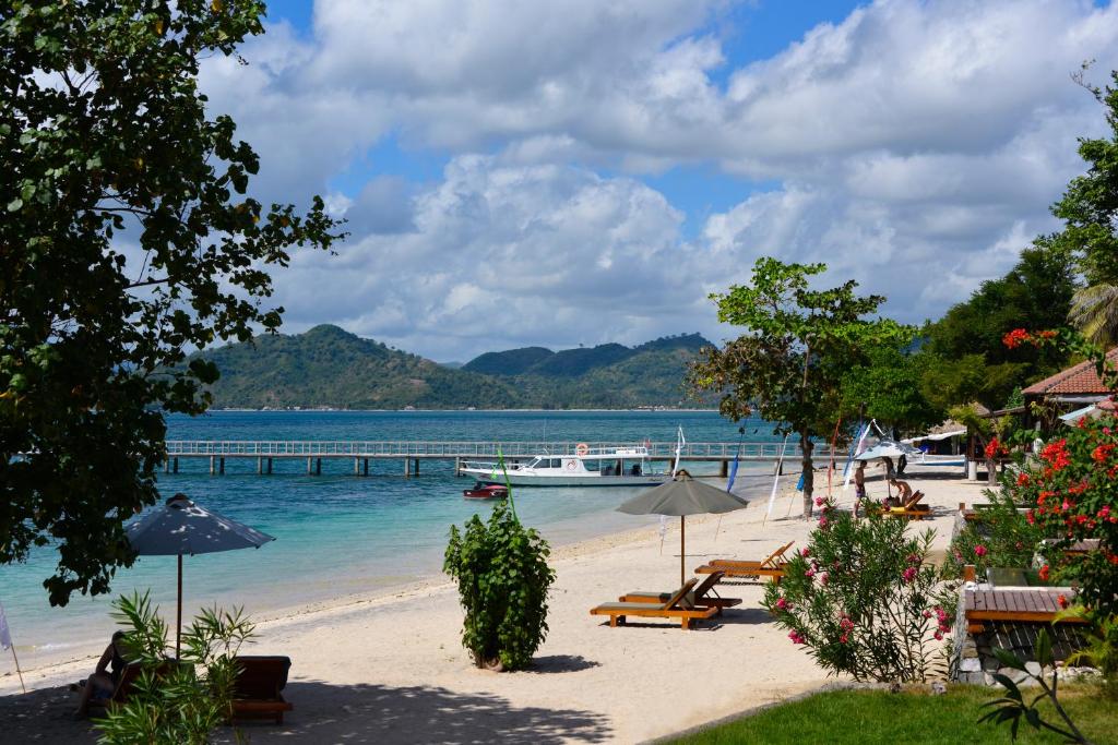 a beach with a pier and a boat in the water at Cocotinos Sekotong Lombok in Sekotong