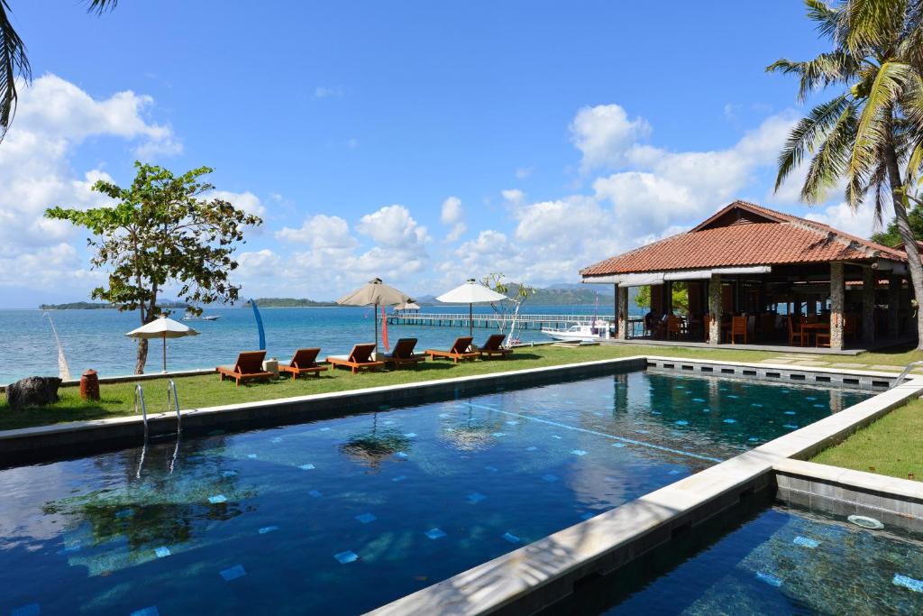 a swimming pool in front of a house with the water at Cocotinos Sekotong Lombok in Sekotong