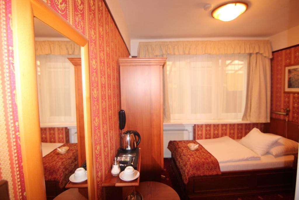 a small bedroom with a bed and a mirror at Old Prague Hotel in Prague