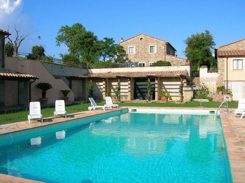 a swimming pool with two chairs and a house at Le Murelle Country Resort in Manciano