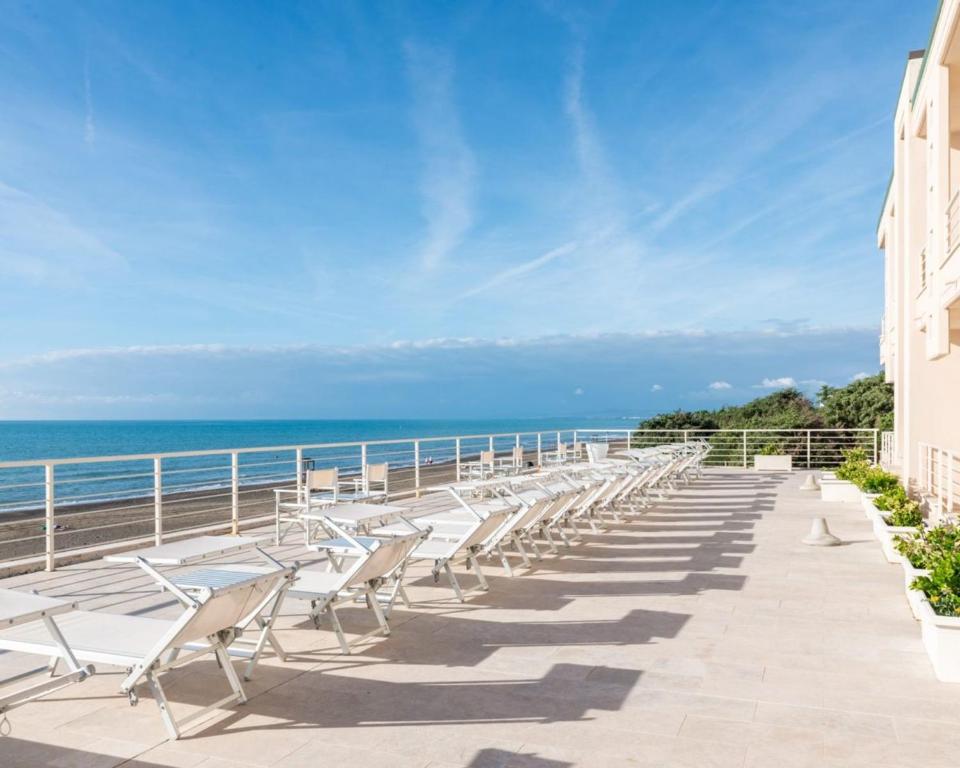 una fila di sedie su un balcone con vista sull'oceano di Hotel Alta La Vista a Marina di Castagneto Carducci