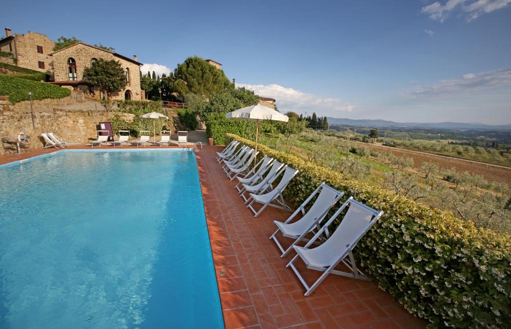 uma fila de cadeiras brancas sentadas ao lado de uma piscina em La Terrazza di Cinciano em Poggibonsi