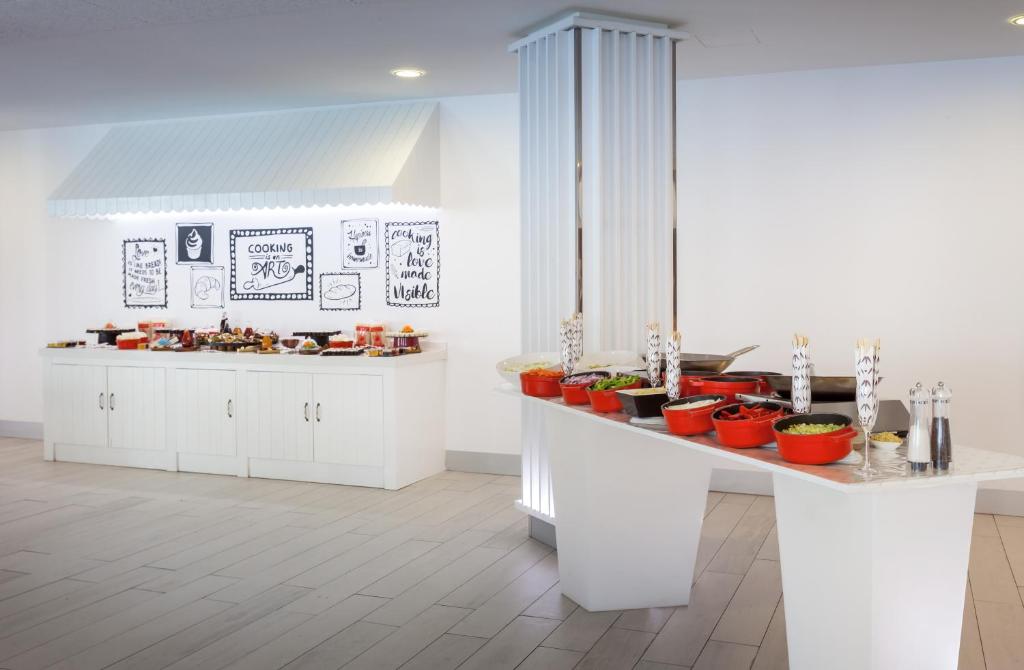 a kitchen with white cabinets and red pots on a counter at Barceló Corralejo Sands in Corralejo