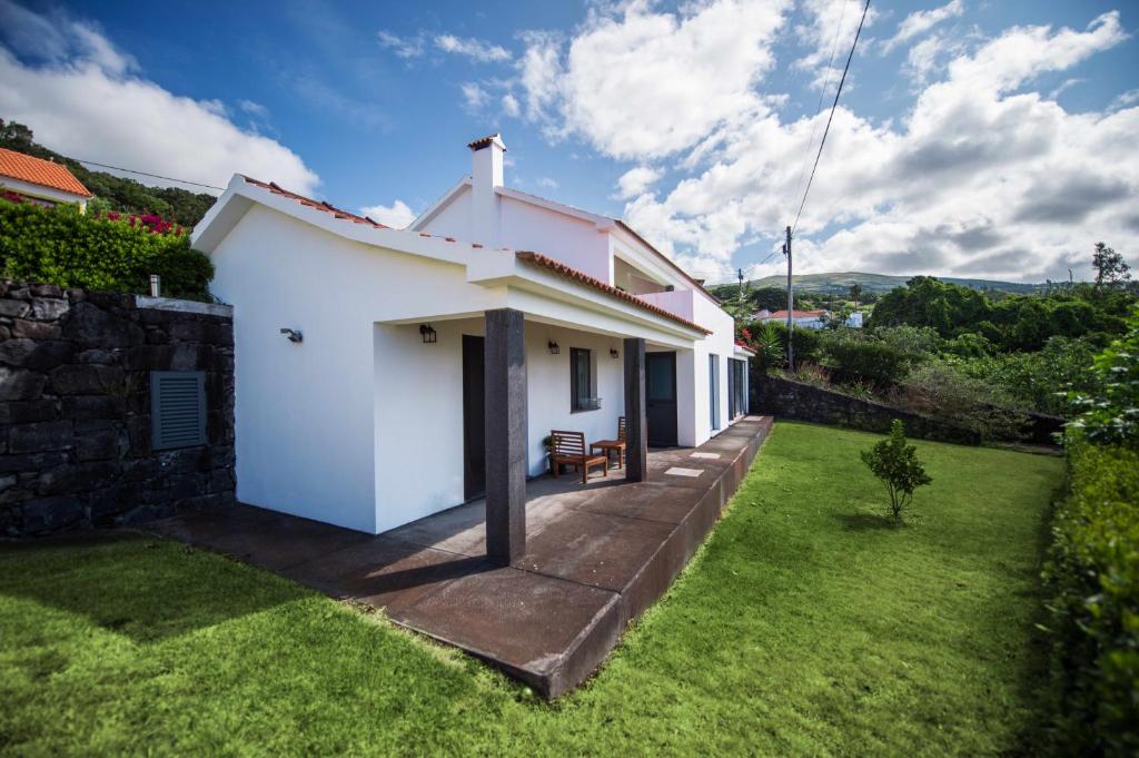uma pequena casa branca com um jardim de relva em Casa do Nuno T1 em Horta