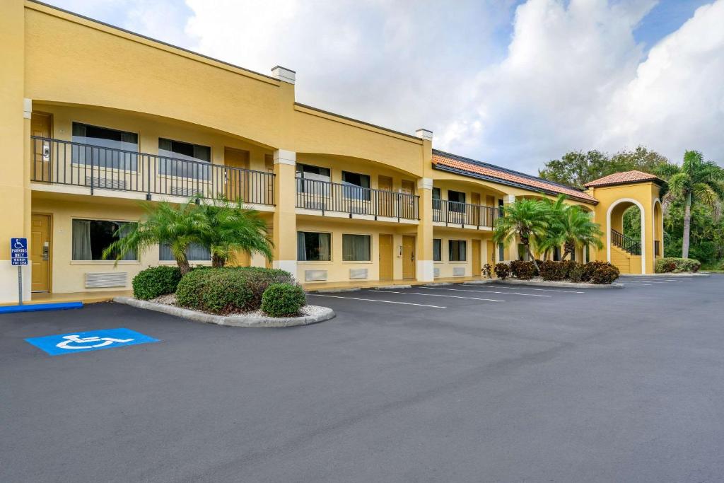 ein großes gelbes Gebäude mit Palmen auf einem Parkplatz in der Unterkunft Comfort Inn Sun City Center - Ruskin - Tampa South in Sun City Center