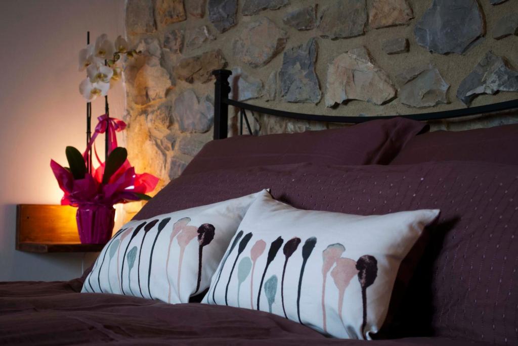 a bedroom with a bed with pillows with a stone wall at B&B Lavanda e Rosmarino in Capolona