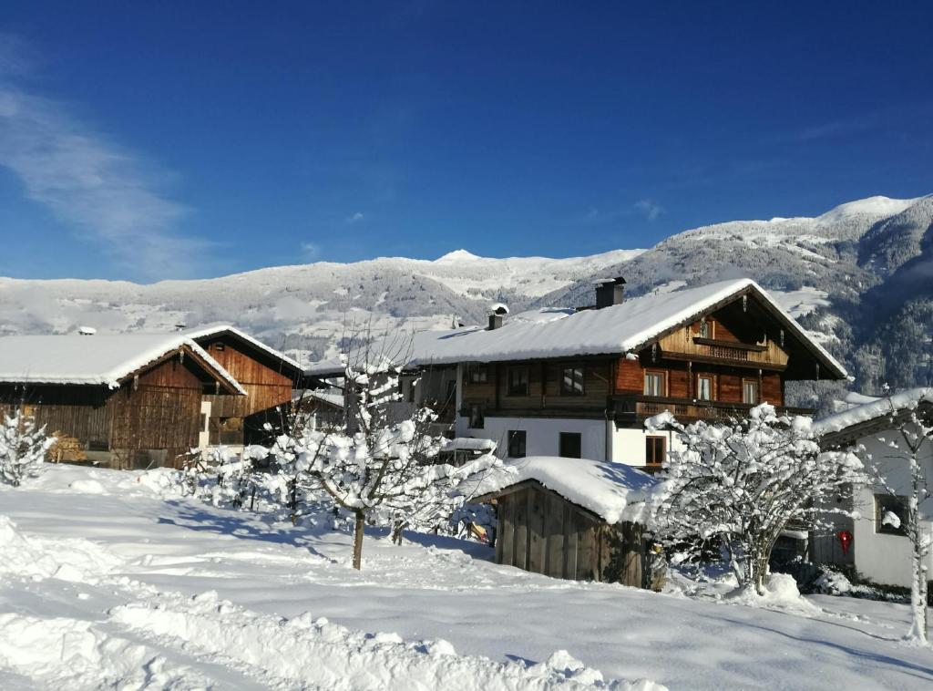 een huis bedekt met sneeuw met bomen en bergen bij Ferienhaus Oberhuben in Fügenberg