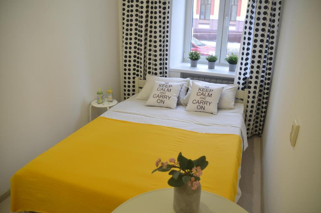 um pequeno quarto com uma cama com lençóis e almofadas amarelas em Гостиница City House em Yaroslavl