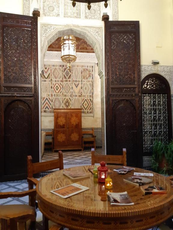 comedor con mesa, sillas y pared en Riad Fes Palacete, en Fez
