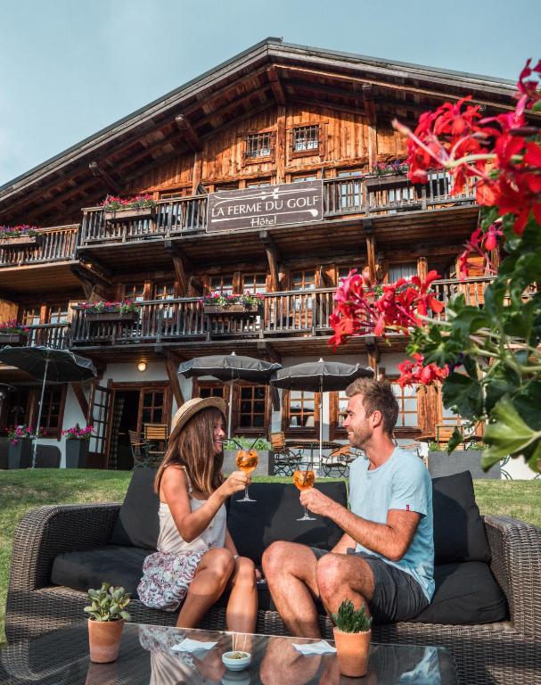 a man and a woman sitting on a couch in front of a building at La Ferme du Golf in Megève