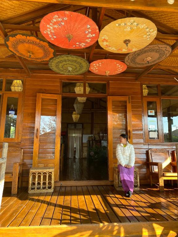 una persona in piedi su un portico con ombrelloni sul soffitto di Trinity Family Inn a Nyaung Shwe